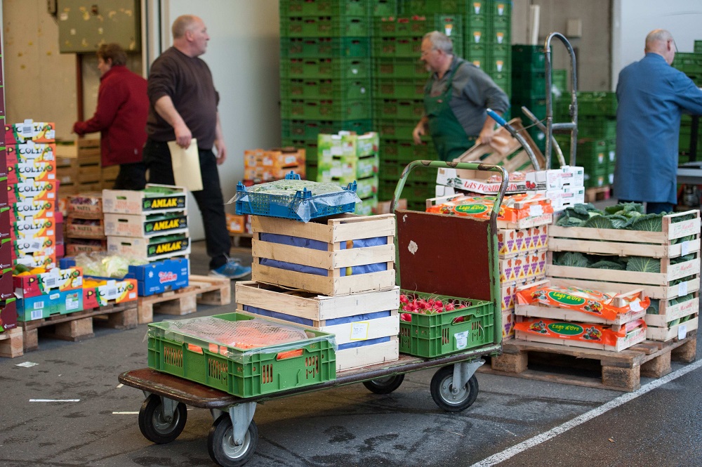 Händler stehen umringt von Obst- und Gemüsekisten auf dem Großmarkt in Freiburg.